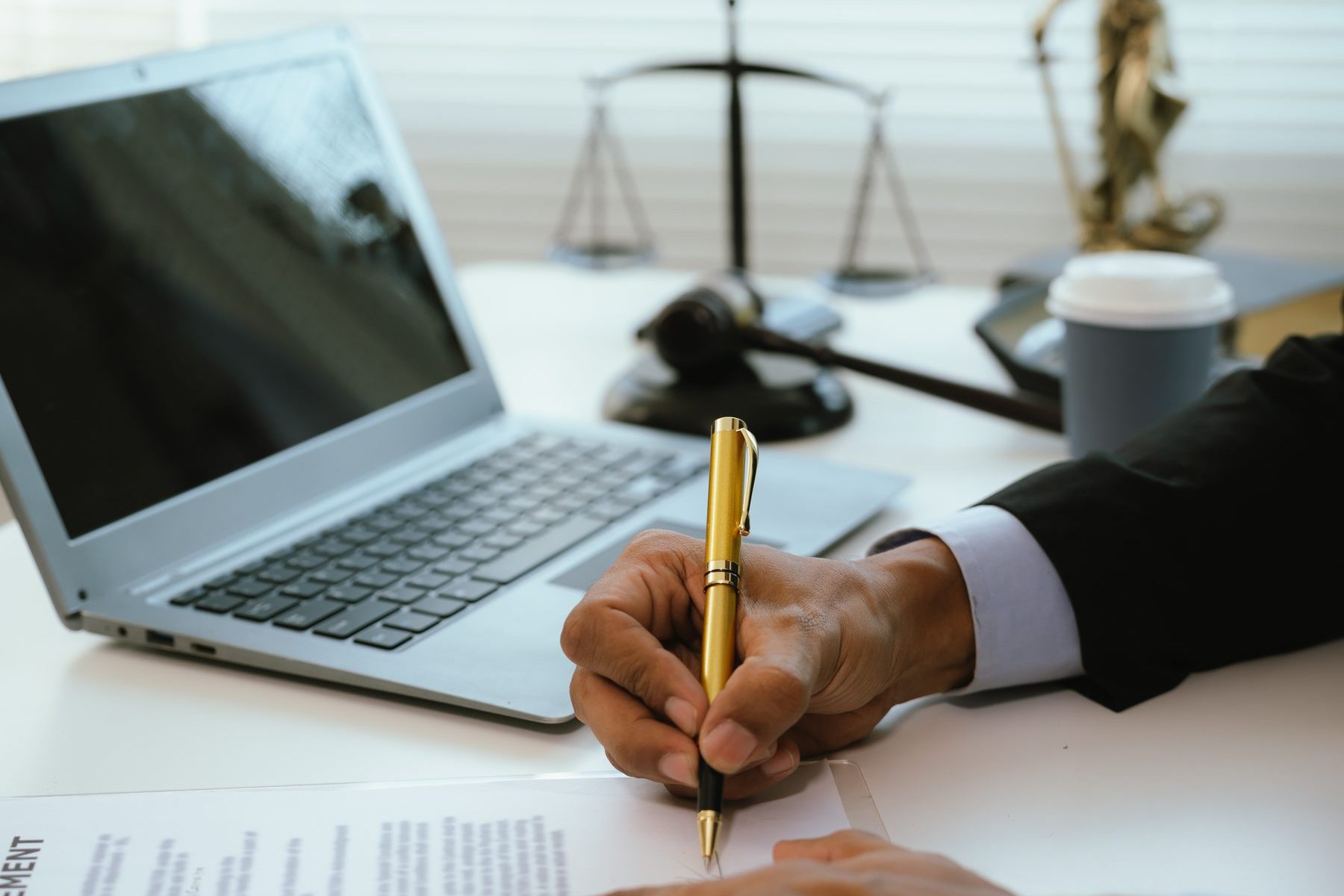 Schreibtisch mit Justitia-Figur, Laptop und Unterlagen